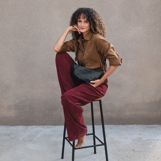 Woman sitting on a stool against a plain wall