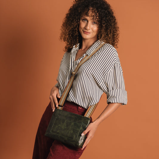 Woman holding a green handbag against a brown background