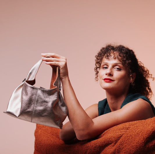 Woman holding a silver handbag against a plain background