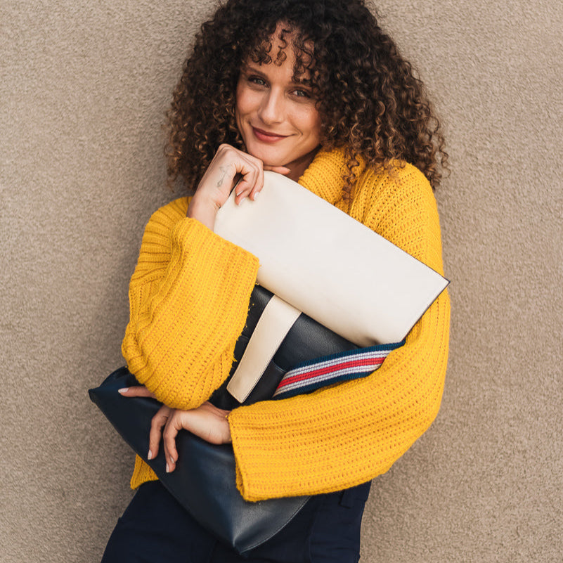 Woman in a yellow sweater holding a book against a beige wall