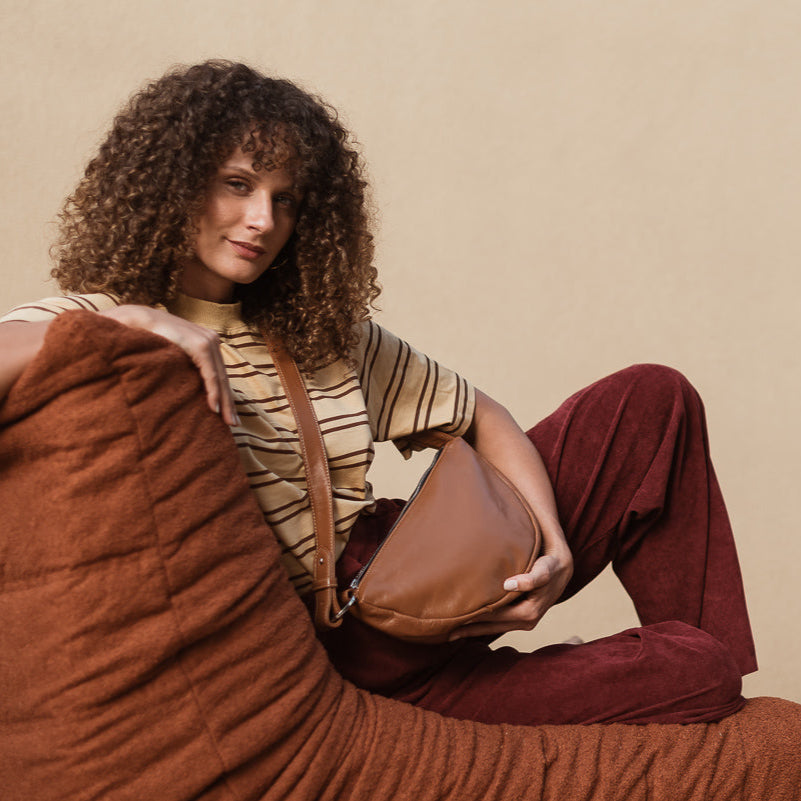 Woman sitting on a brown couch against a beige background