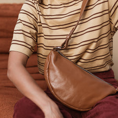 Person wearing a striped shirt and holding a brown leather bag.