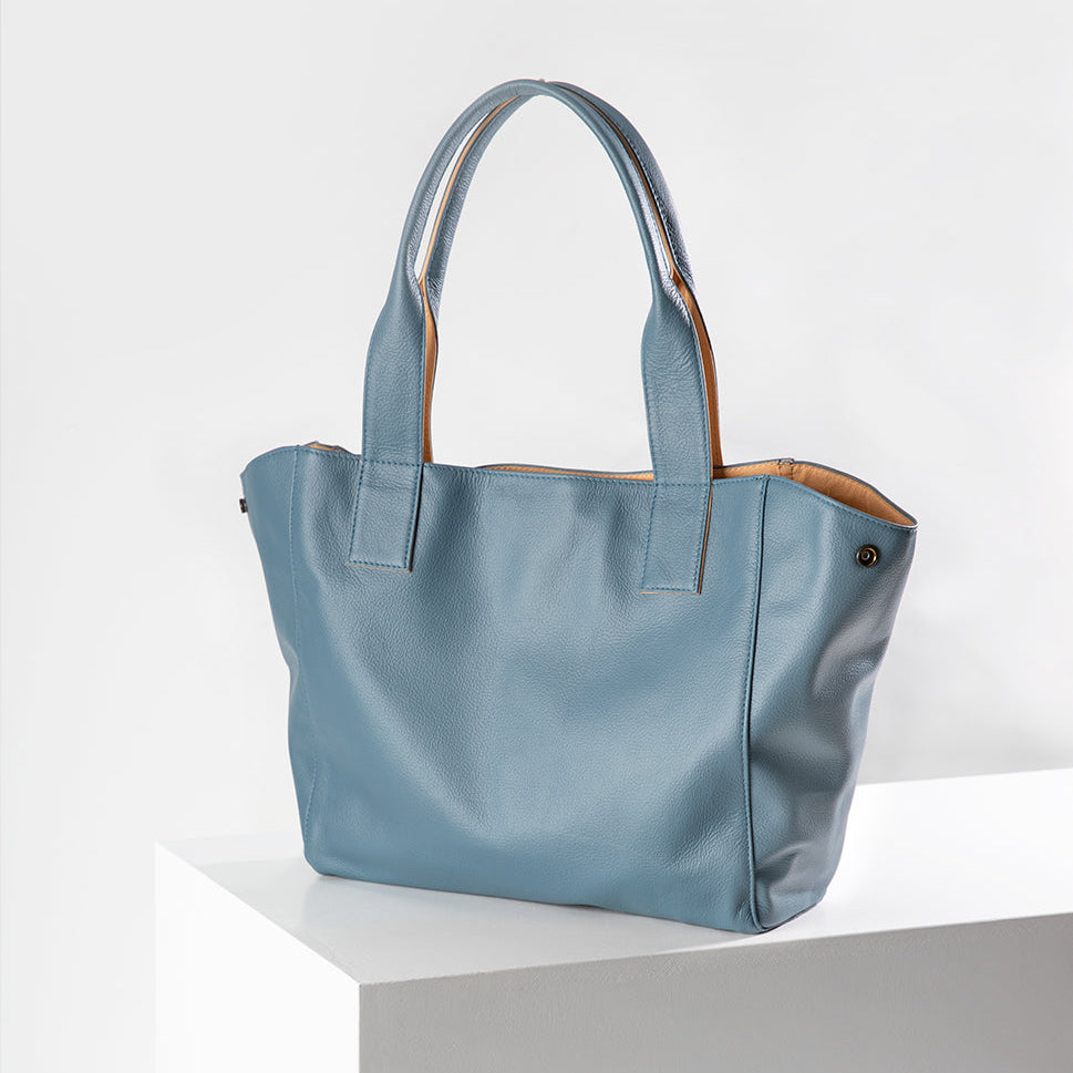 Blue handbag on a white pedestal with a white background