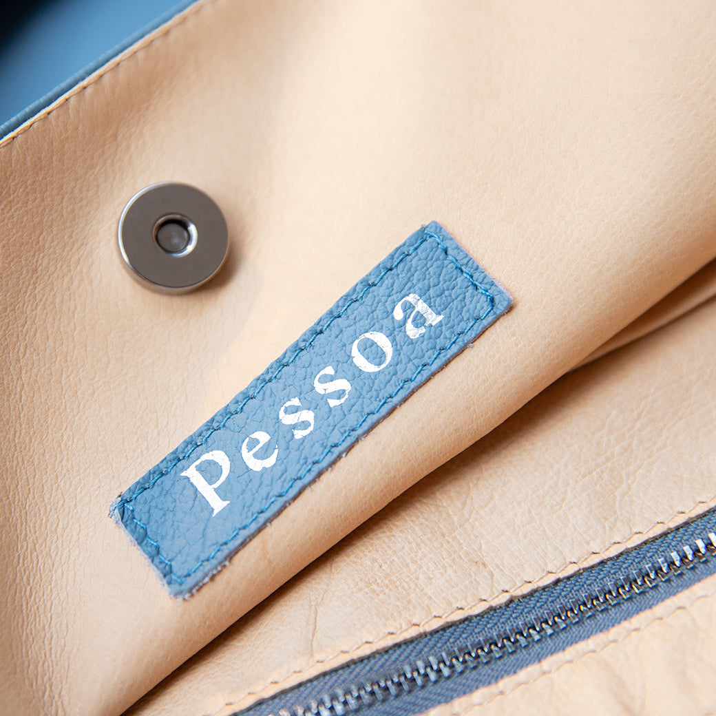 Close-up of a beige leather product with a blue label featuring the word 'Pessoa'.