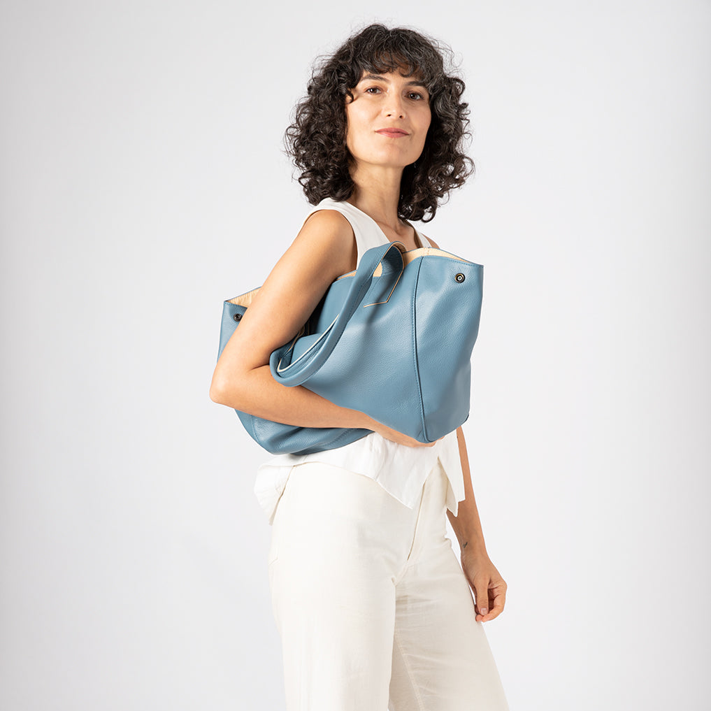 Woman holding a blue tote bag against a white background