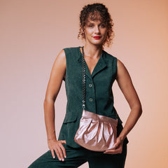 Woman in a green outfit holding a pink handbag against a gradient background leather bag