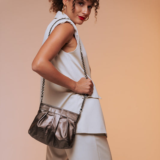 Woman holding a metallic handbag against a beige background
