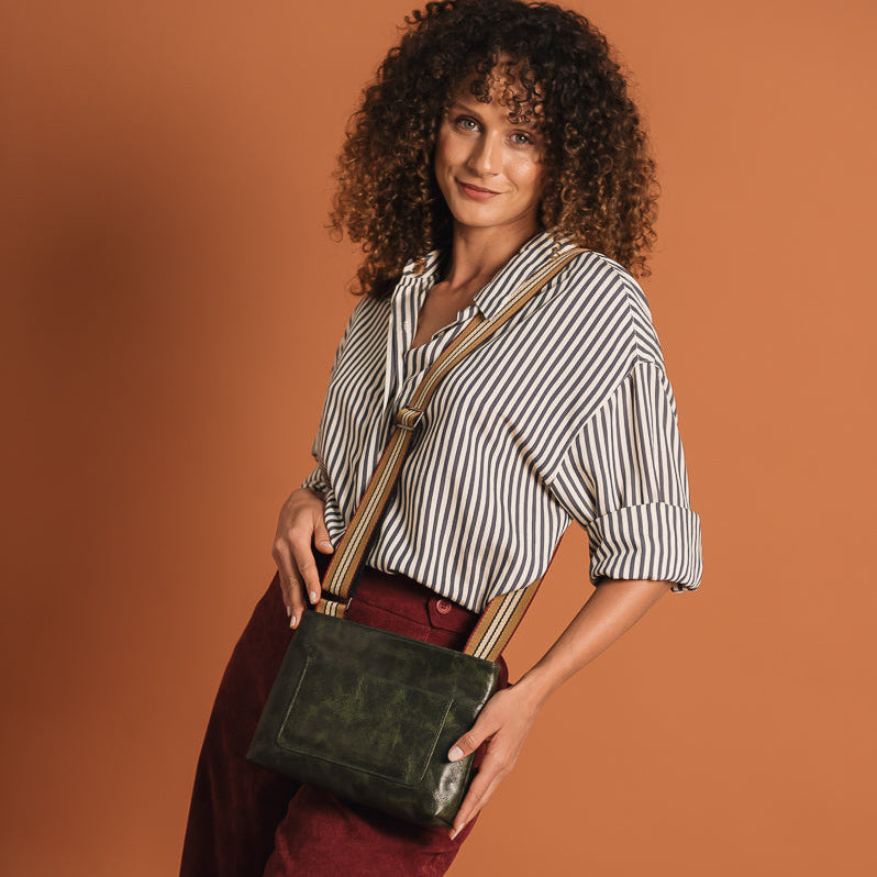 Woman holding a green handbag against a brown background