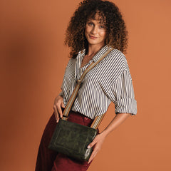 Woman holding a green handbag against a brown background