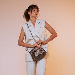 Woman in a white outfit holding a black handbag against a gradient background