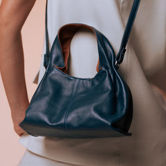 Person wearing a navy blue leather handbag with a brown interior on a beige background